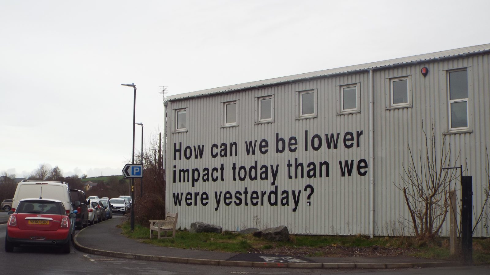 Building showing large graffitti "How can we be lower impact today than we were yesterday?"